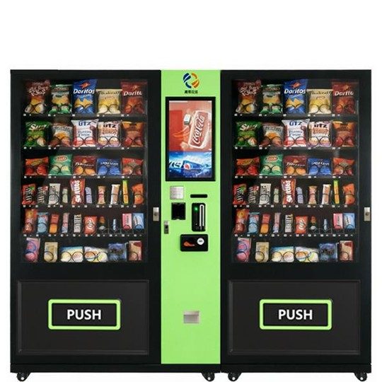 Two modern black and lime green vending machines side-by-side, fully stocked with various snacks and bottled drinks for high-traffic locations.